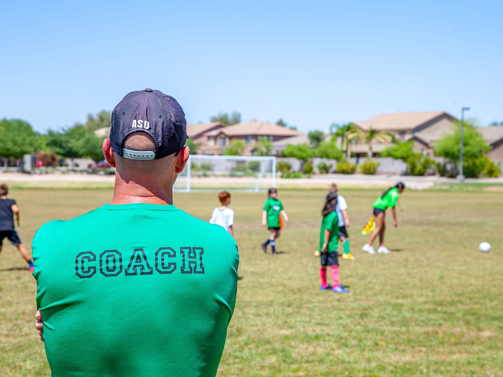 A coach watching a youth football session from the touchline